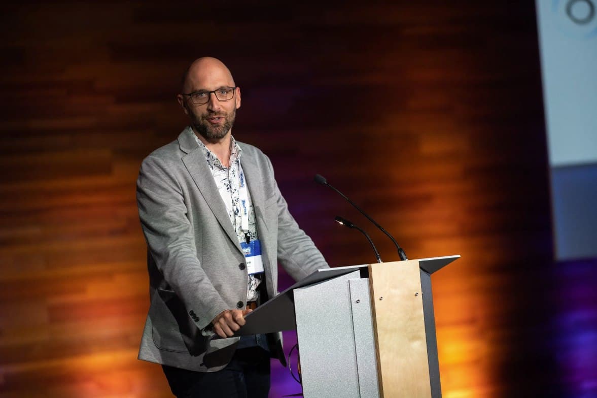 Adam Tank speaking on stage at a water industry conference